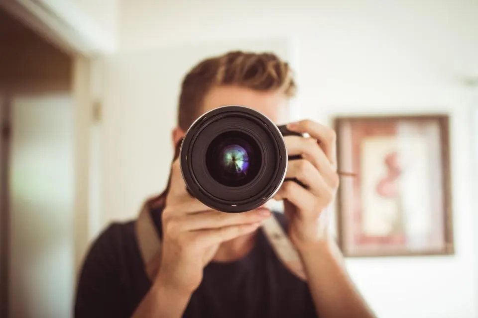 Photographer holding a camera lens up to the viewer